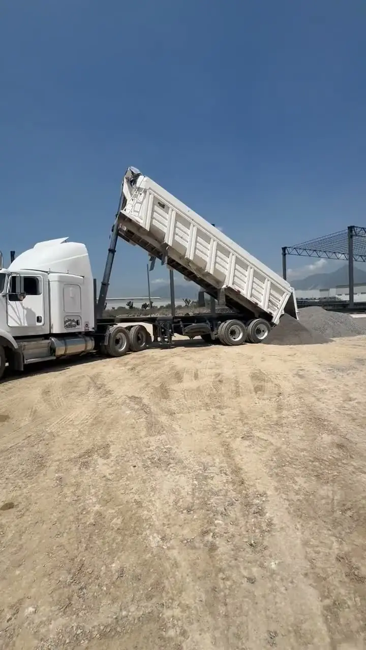 Camión de volteo descargando material en obra